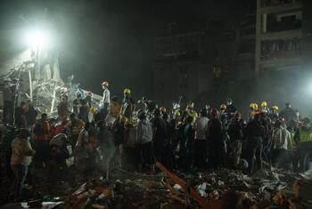 Rescue workers in yellow helmets search through rubble at a collapsed building site in Venezuela following an earthquake.