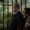 Um homem e uma mulher venezuelanos estão lado a lado atrás de uma cerca à noite, desviando o olhar com expressões de tristeza e preocupação após o terremoto de 2026.