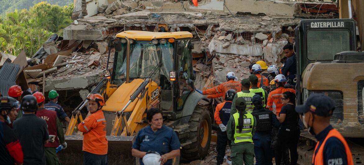 Los equipos de rescate y el personal de emergencia se congregan alrededor de un edificio derrumbado y maquinaria pesada en el lugar del terremoto.