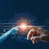 Au centre de l'image, une main robotique et une main humaine se touchent du bout des doigts, un point de contact lumineux. L'arrière-plan représente un réseau numérique bleu foncé composé de lignes de circuit et de code binaire.