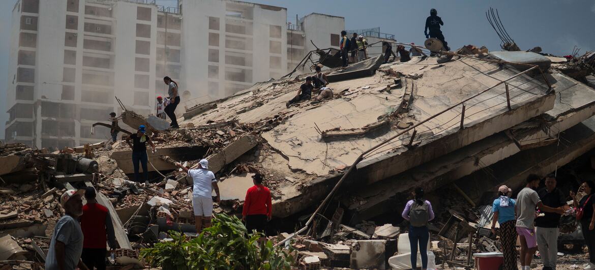 Equipes de busca e sobreviventes vasculham os escombros de um prédio que desabou em La Guaira, Venezuela, após grandes terremotos.