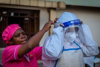 Une sage-femme en uniforme rose aide une collègue à ajuster une visière de protection lors d'une séance pratique sur les EPI au Nord-Kivu.