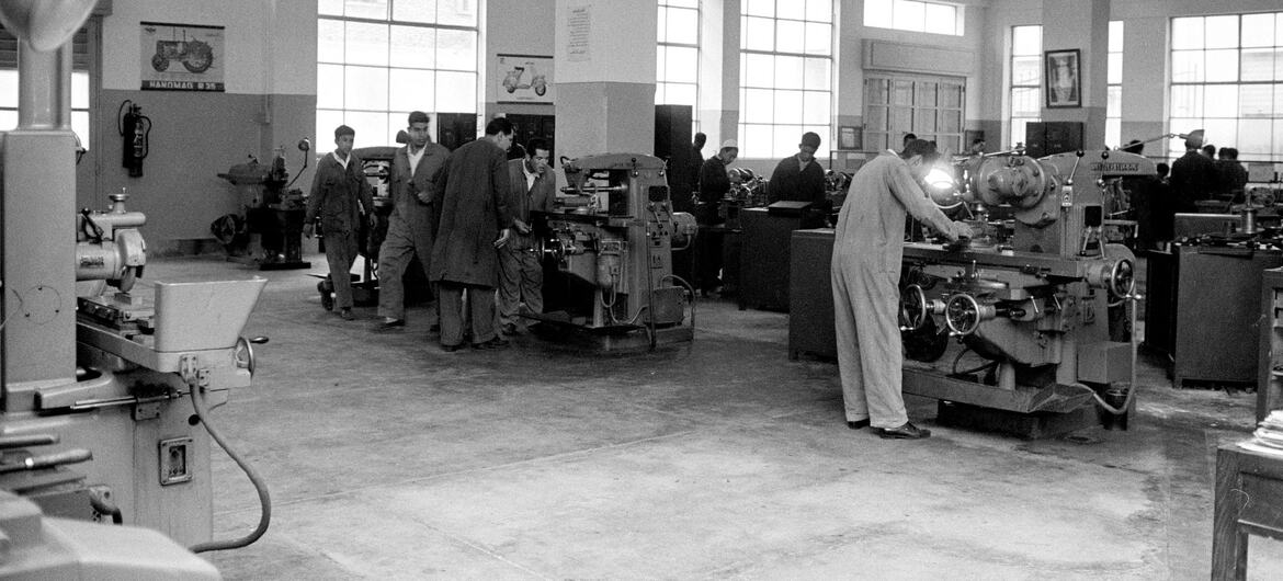 Overall view of a class in the machine shop at the Technical and Clerical Training Centre in Tripoli, Libya, with teachers and students operating industrial machinery.