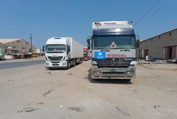 WHO trucks carrying medical supplies are parked on a dusty road in Sudan.