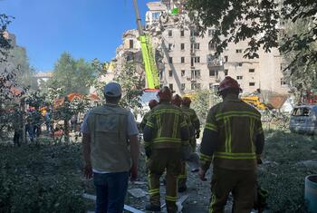 UNICEF staff and firefighters walk towards a heavily damaged building during a rescue operation in Kyiv, Ukraine.