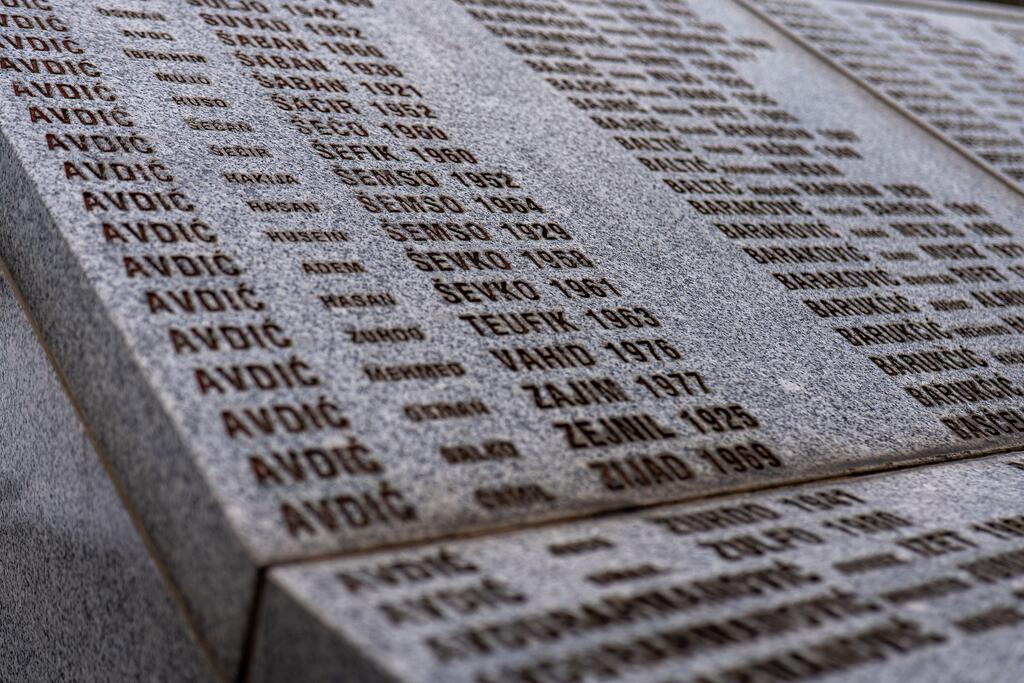Gros plan sur une pierre commémorative portant gravés les noms et dates des victimes du génocide de Srebrenica.
