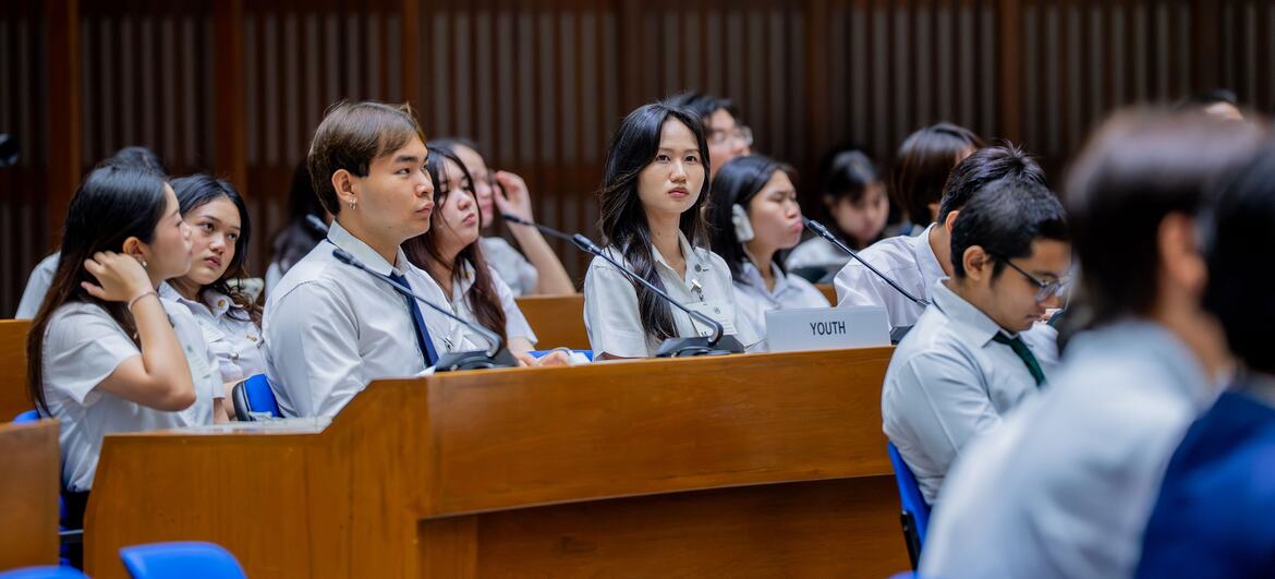 Young people in white shirts sit at a conference table with microphones at a youth roundtable event in Thailand.