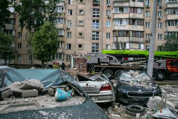 Damaged cars and debris in front of a damaged apartment building in Kyiv, Ukraine, following a drone and missile attack.