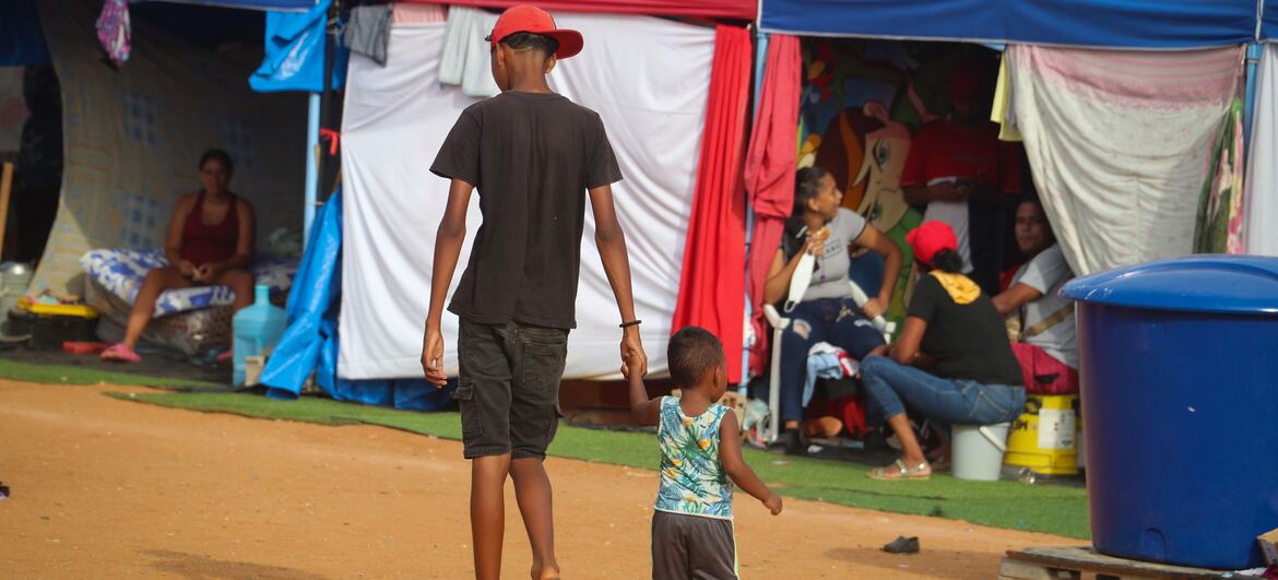 Dos niños, un niño y un bebé, caminan de la mano por un refugio provisional en La Guaira, Venezuela, tras un terremoto.