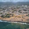 Aerial view of the coastal city of La Guaira, Venezuela, showing extensive earthquake rubble and a reconstruction site.