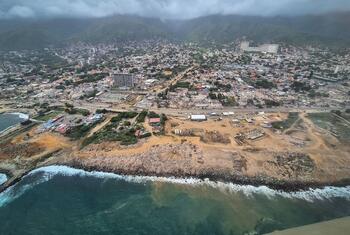 Aerial view of the coastal city of La Guaira, Venezuela, showing extensive earthquake rubble and a reconstruction site.