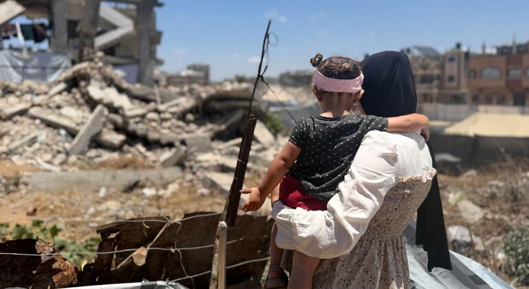 أم فلسطينية تقف مع ابنتها أمام ركام أحد المنازل في قطاع غزة.