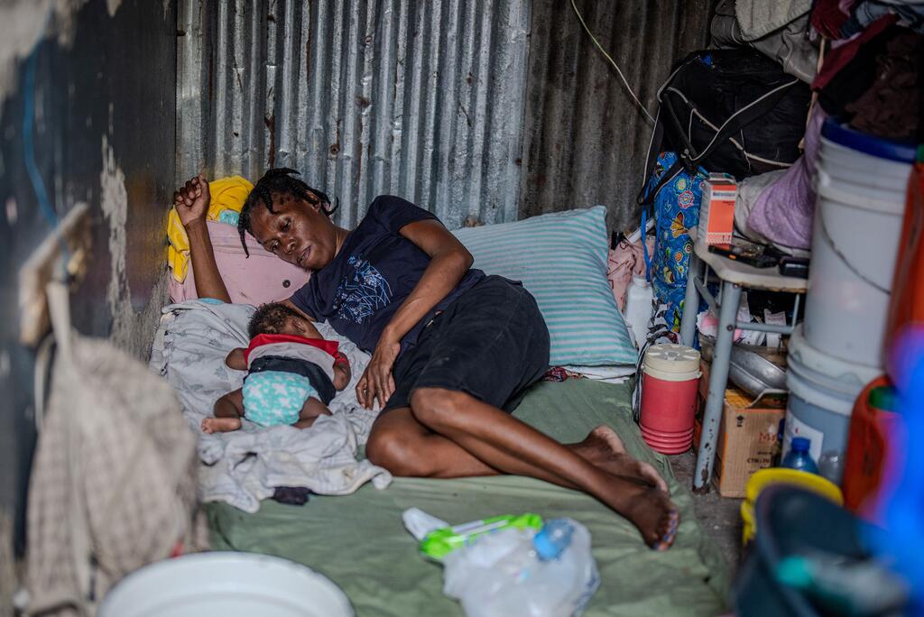 Una mujer y su bebé descansan en un refugio improvisado durante el desplazamiento en Haití.