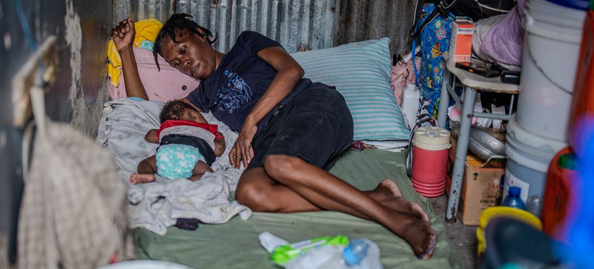 woman and baby rest in a makeshift shelter during displacement in Haiti