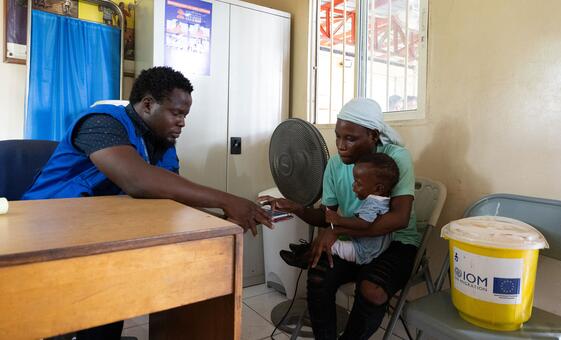Un travailleur humanitaire de l'ONU aide une femme et à son enfant qui ont été rapatriés de force en Haïti.