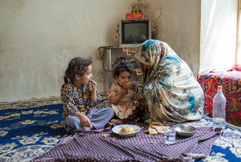 An Afghan mother shares a meal with her two young daughters inside their home.