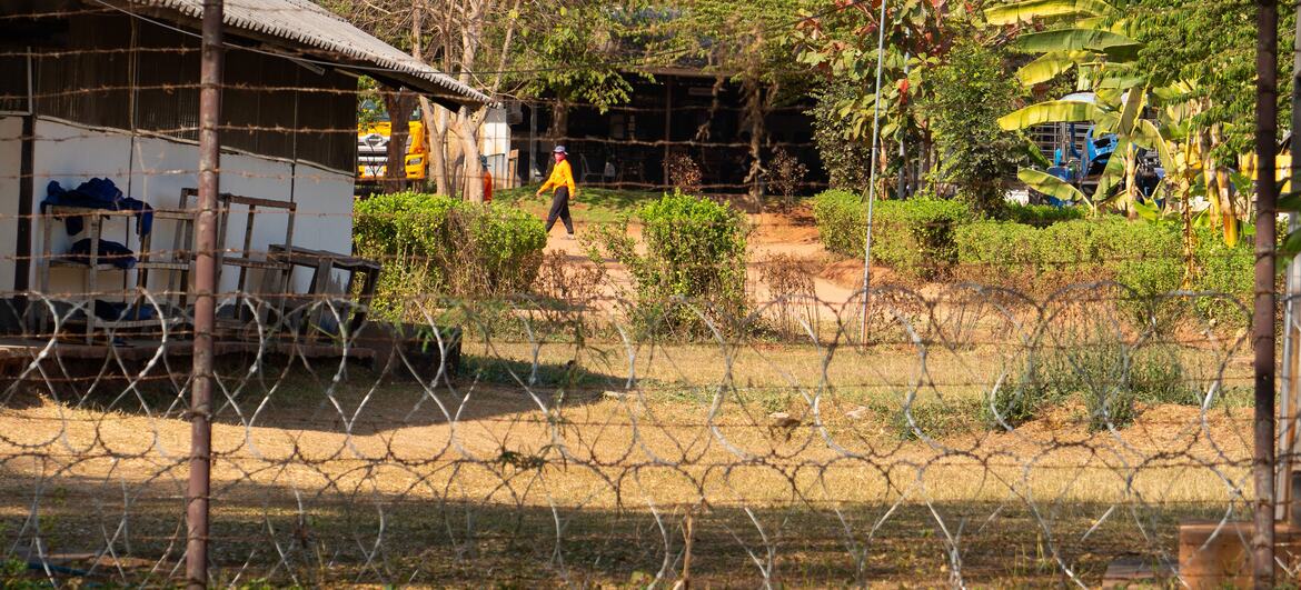A person walks behind a barbed wire fence at a correctional facility in rural Thailand.
