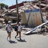 Dos jóvenes caminan por una calle pública junto a un edificio derrumbado en Catia La Mar, La Guaira, Venezuela, tras un terremoto.