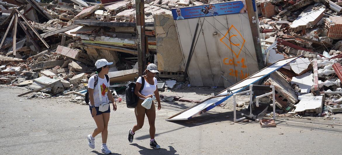 Dos jóvenes caminan por una calle pública junto a un edificio derrumbado en Catia La Mar, La Guaira, Venezuela, tras un terremoto.
