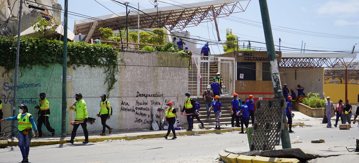 Personal de emergencia y equipos de rescate permanecen apostados frente a un edificio derrumbado en La Guaira, Venezuela, donde se han escrito en una pared los nombres de las personas desaparecidas.