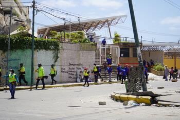 Personal de emergencia y equipos de rescate permanecen apostados frente a un edificio derrumbado en La Guaira, Venezuela, donde se han escrito en una pared los nombres de las personas desaparecidas.