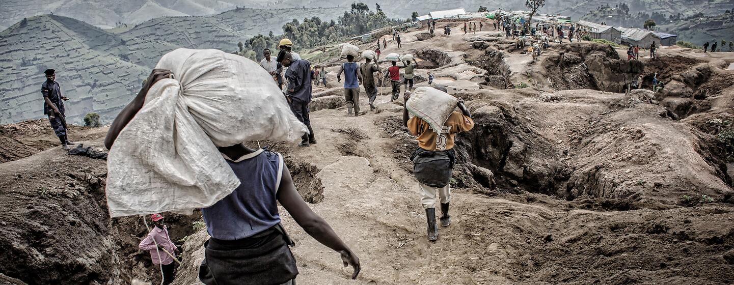 Des mineurs artisanaux transportent de gros sacs de minéraux sur un flanc de colline escarpé à la mine de Mudere, dans la région du Nord-Kivu, en République démocratique du Congo.