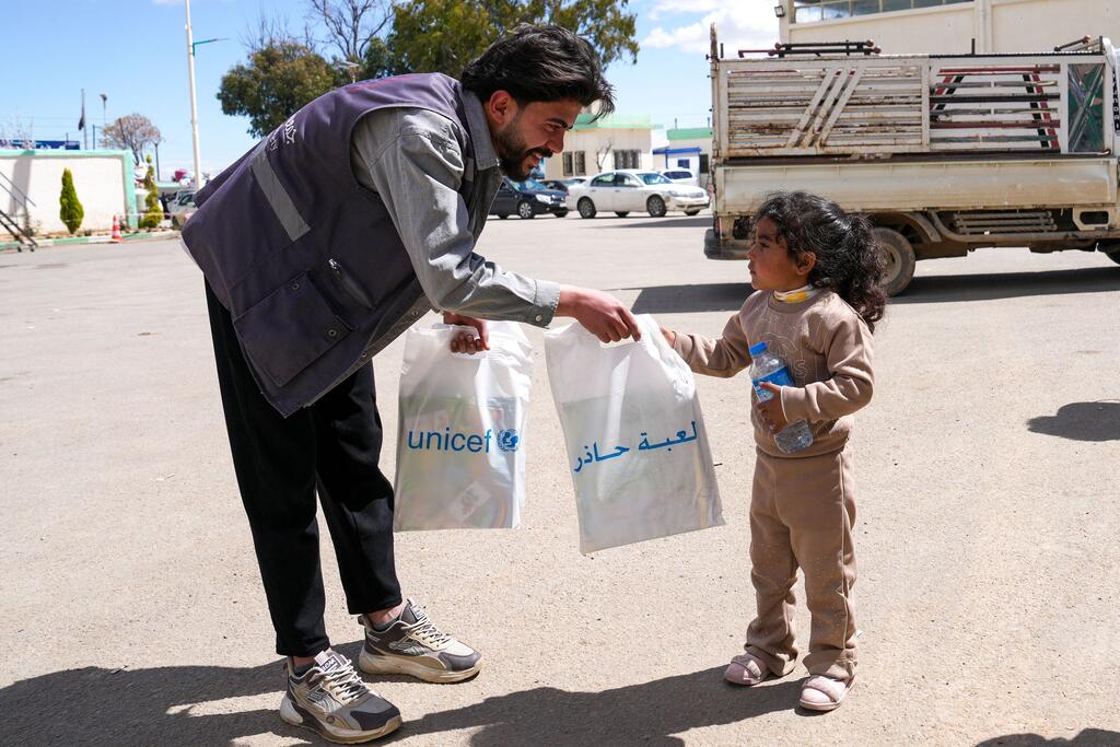 Mfanyakazi anayeungwa mkono na UNICEF akimpa msichana mdogo kifaa cha kuelimisha kuhusu hatari ya mabomu kwenye mpaka nchini Syria.