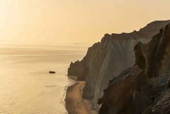 Les falaises rocheuses rouges de l'île d'Ormuz en Iran, bordant la mer au coucher du soleil.