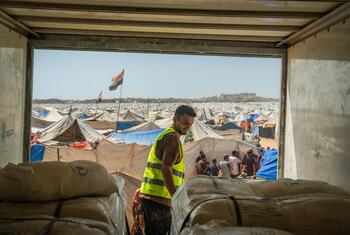 يقف عامل من WFP في شاحنة، وينظر إلى مخيم كبير للاجئين في غزة مليء بالخيام والنازحين.