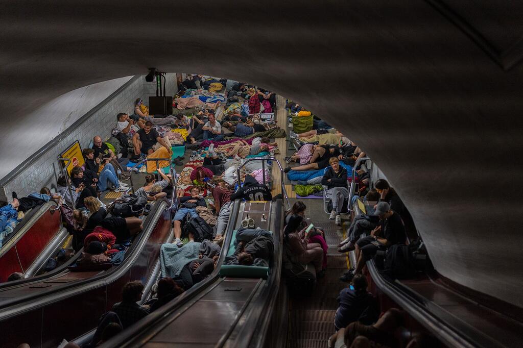 Une station de métro bondée à Kyiv, en Ukraine, où des familles s'étaient réfugiées après les bombardements aériens de la nuit précédente. On y voit des personnes, y compris des enfants, dormir ou se reposer à même le sol et sur les escaliers mécaniques.