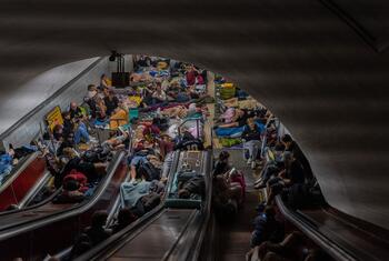 Una concurrida estación de metro de Kiev, en Ucrania, repleta de familias que se refugiaban de los ataques aéreos nocturnos. Se puede ver a personas, incluidos niños, durmiendo y descansando en el suelo y en las escaleras mecánicas.