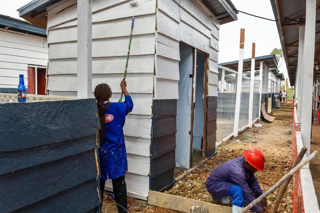 Des ouvriers du bâtiment à Rwankole, dans la province d'Ituri, en RDC, peignent et préparent l'extérieur d'un nouveau centre de traitement d'Ebola en juillet 2026.