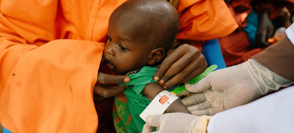 A WFP worker measures the arm of a young Somali child being held by a caregiver in Burhakaba.