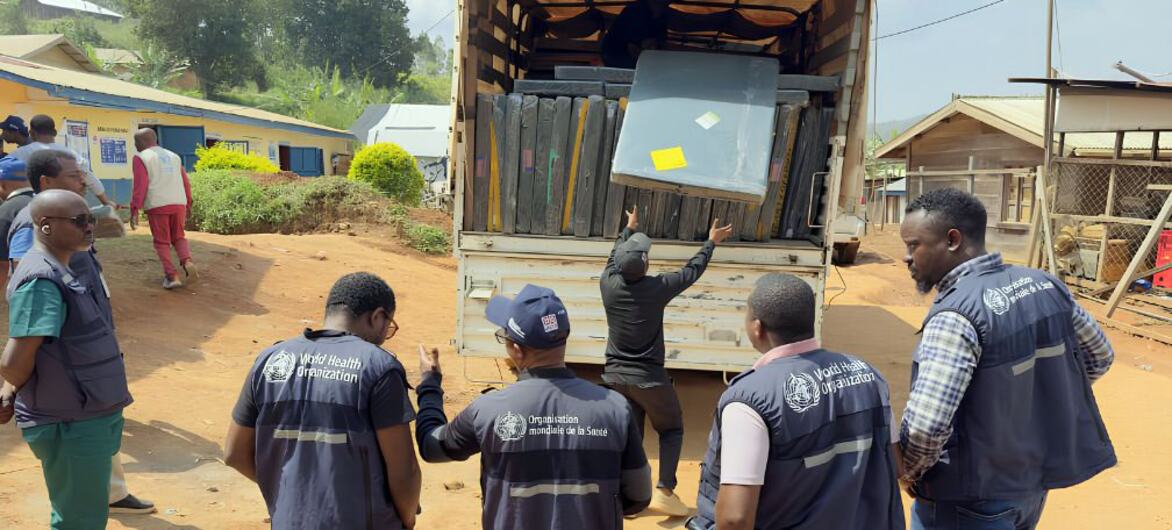Des travailleurs humanitaires de l'OMS à Nizi, en RDC, déchargent des matelas et des lits d'un camion afin d'augmenter la capacité d'un centre de traitement d'Ebola.