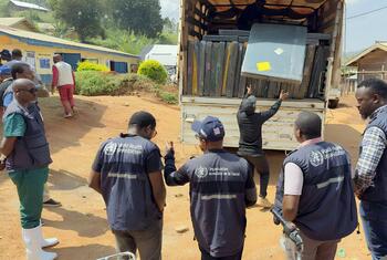 Des travailleurs humanitaires de l'OMS à Nizi, en RDC, déchargent des matelas et des lits d'un camion afin d'augmenter la capacité d'un centre de traitement d'Ebola.