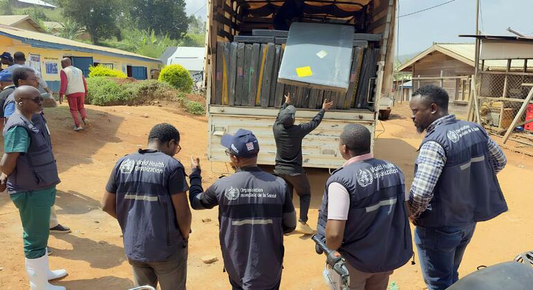 Des travailleurs humanitaires de l'OMS à Nizi, en RDC, déchargent des matelas et des lits d'un camion afin d'augmenter la capacité d'un centre de traitement d'Ebola.