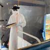 Un agent de santé en tenue de protection complète se tient à l'intérieur d'un centre de traitement d'Ebola à Nizi, en RDC, en train d'examiner un dossier médical.