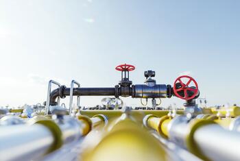 Estación de servicio de gas natural con sistema de tuberías que incluye válvulas industriales y tuberías amarillas bajo un cielo despejado.