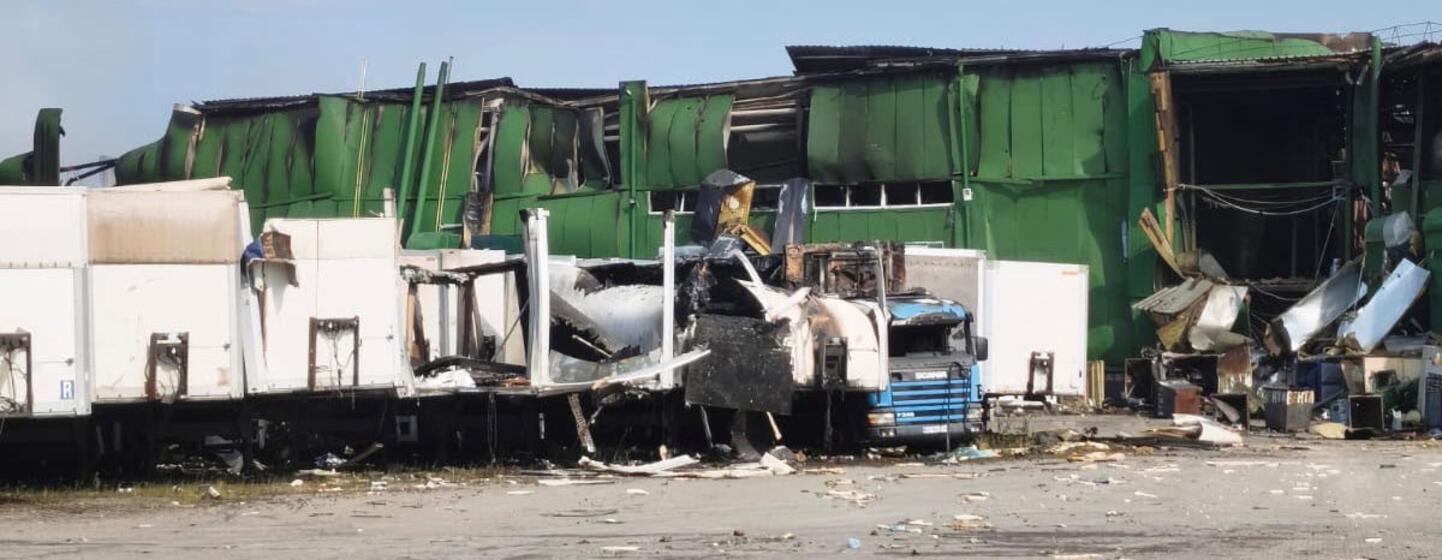 Entrepôt vert détruit et camions endommagés à Dnipro, en Ukraine.