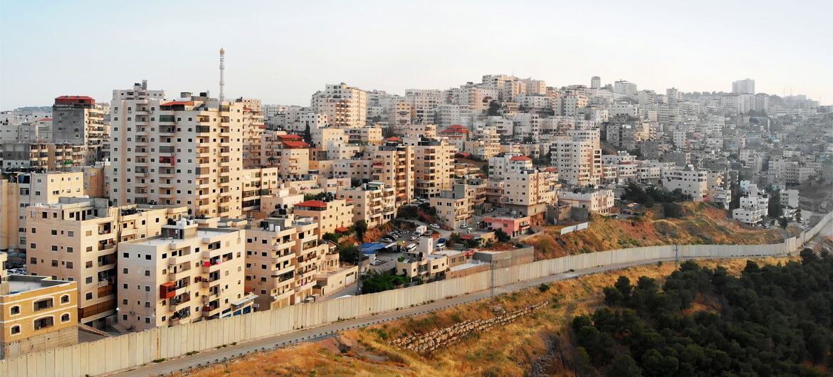 Aerial view of Palestinian town Shuafat near Jerusalem with a concrete separation barrier in the foreground.