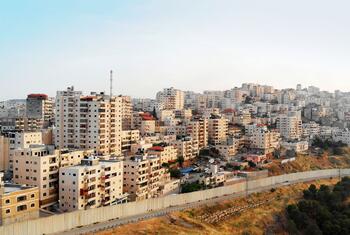 Aerial view of Palestinian town Shuafat near Jerusalem with a concrete separation barrier in the foreground.