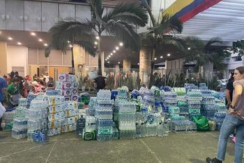Grandes pilas de agua embotellada y suministros de ayuda humanitaria se acumulan frente a un edificio en Cali, Colombia, tras un terremoto.