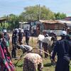 UNMISS police officers in blue helmets and uniforms stand among civilians working in a rural settlement in Kodok, South Sudan.