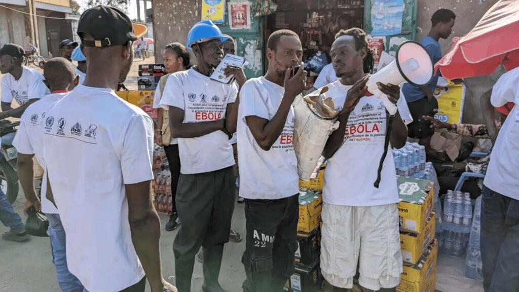 Wapiganaji wa zamani huko Ituri, DR Congo, wakiwa wamevaa fulana nyeupe zenye nembo za Ebola, wanaongoza kampeni ya uhamasishaji umma dhidi ya Ugonjwa wa Virusi vya Ebola kwa usaidizi kutoka MONUSCO.