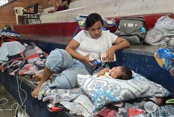 A woman and a baby resting on blankets and pillows in a makeshift shelter inside a boxing coliseum in Quibdó, Colombia.