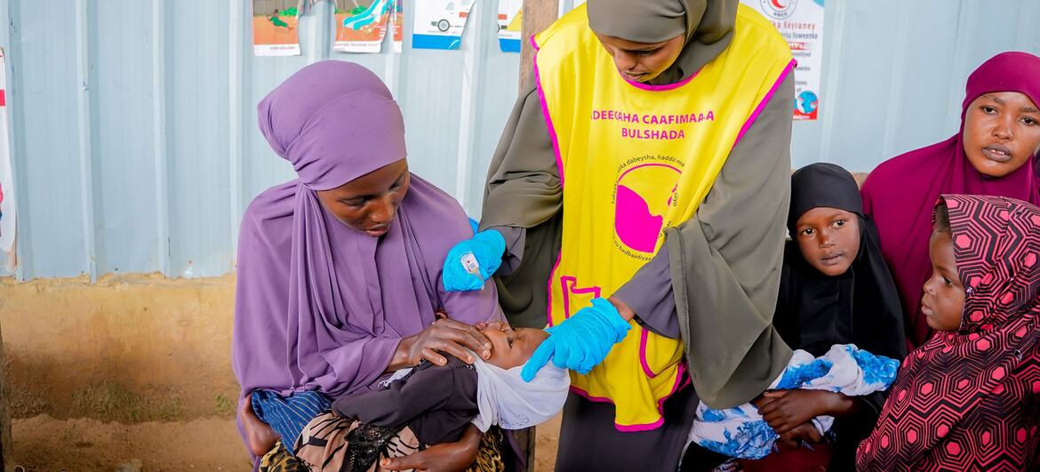 Mfanyakazi wa afya wa Somalia akimpa mtoto mchanga aliyeshikiliwa na mama yake chanjo ya polio wakati wa kampeni ya chanjo katika Mkoa wa Banadir.