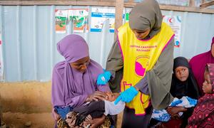 Mfanyakazi wa afya wa Somalia akimpa mtoto mchanga aliyeshikiliwa na mama yake chanjo ya polio wakati wa kampeni ya chanjo katika Mkoa wa Banadir.