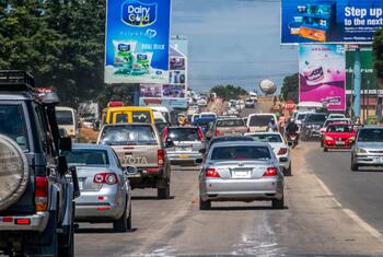 Heavy traffic on the Great East Road in Lusaka, Zambia, with numerous cars and large billboards lining the street.