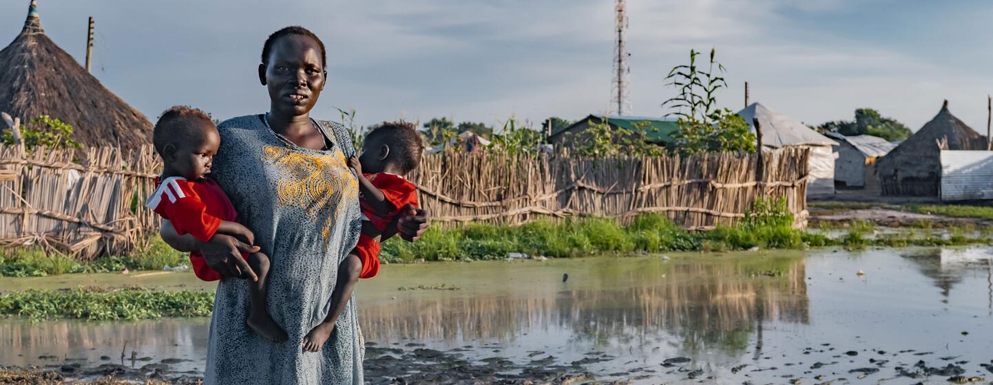 Nyekuola Riek se encuentra en una zona inundada de Sudán del Sur, sosteniendo a sus bebés gemelos.