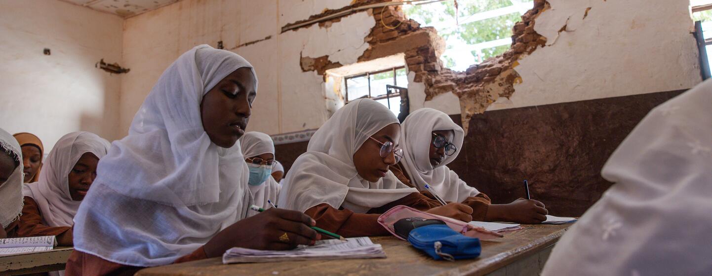 Des élèves portant le hijab assistent à un cours à l'école primaire pour filles Amina Bint Wahb de Khartoum, où les murs et le plafond sont visiblement endommagés.